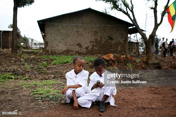 Two boys play with a cellular phone as former U.S. President Bill Clinton tours the Godino Health Center August 1, 2008 in Debre Zeit, Ethiopia....