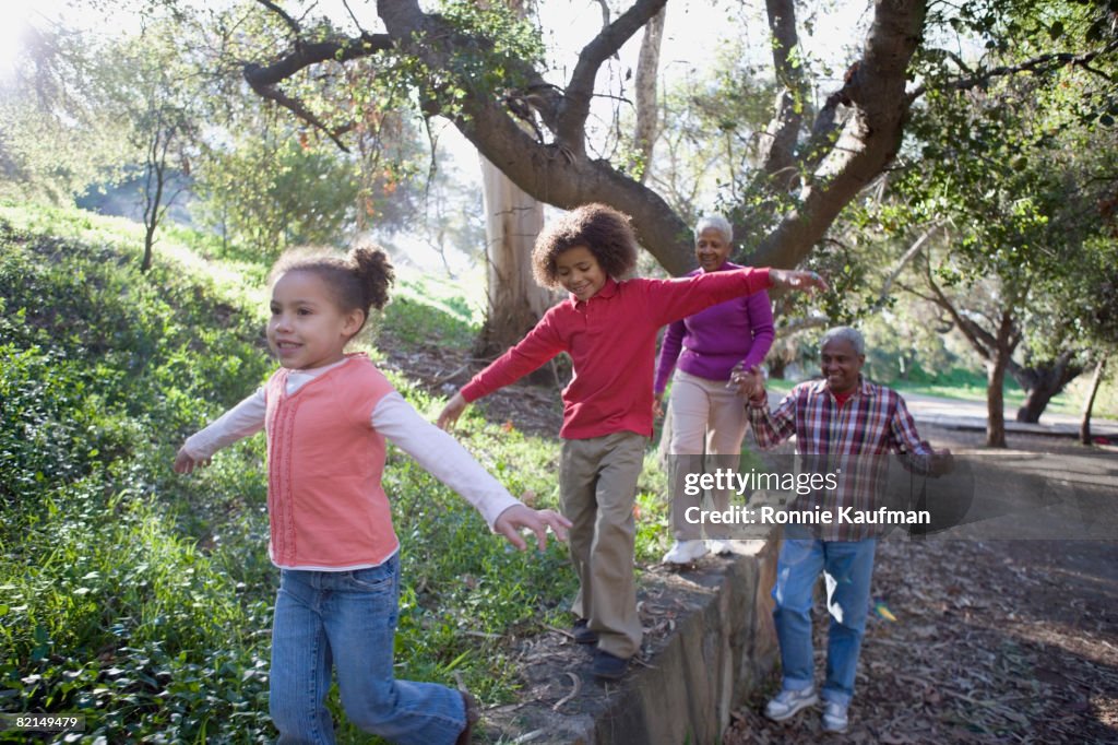 African grandparents and grandchildren walking on wall