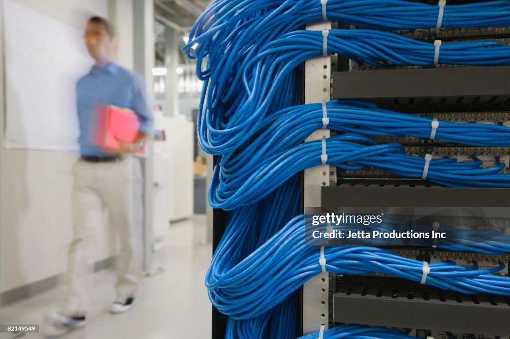 Asian man walking past computer servers