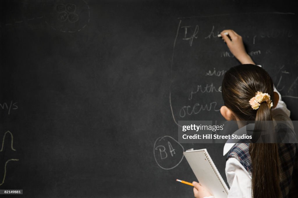 Asian girl writing on blackboard