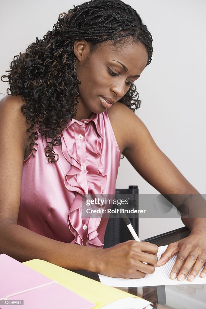 African businesswoman writing at table