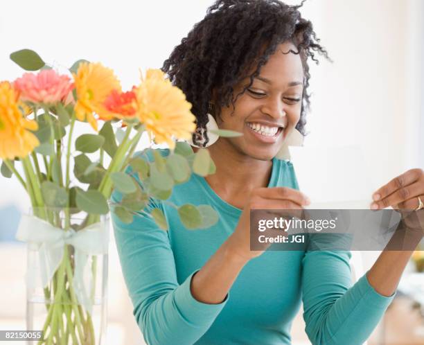 african woman reading card next to flowers - receiving card stock pictures, royalty-free photos & images