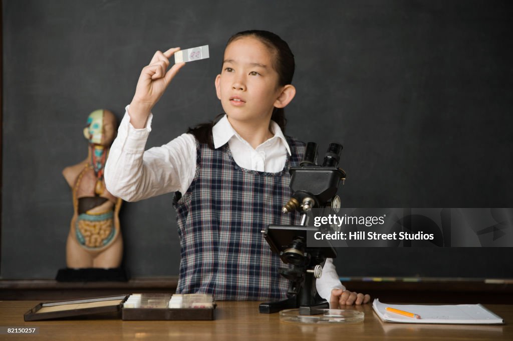 Asian girl looking at microscope slide