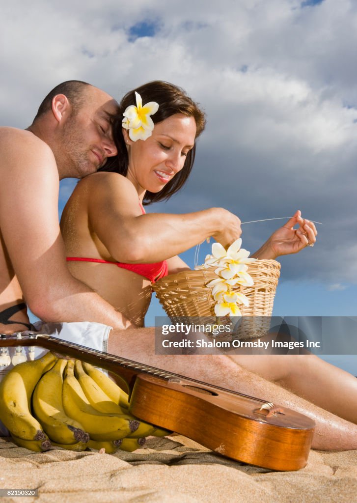 Hispanic couple sitting on beach