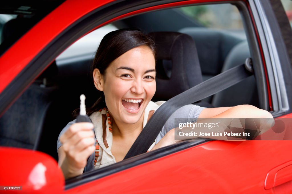 Asian woman holding car key in car