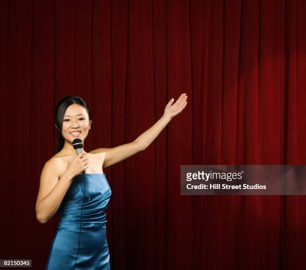 asian woman holding out arm on stage - presentator amusement stockfoto's en -beelden
