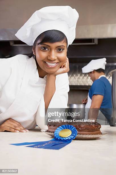 mixed race female pastry chef with blue ribbon and cake - cuca roseta imagens e fotografias de stock