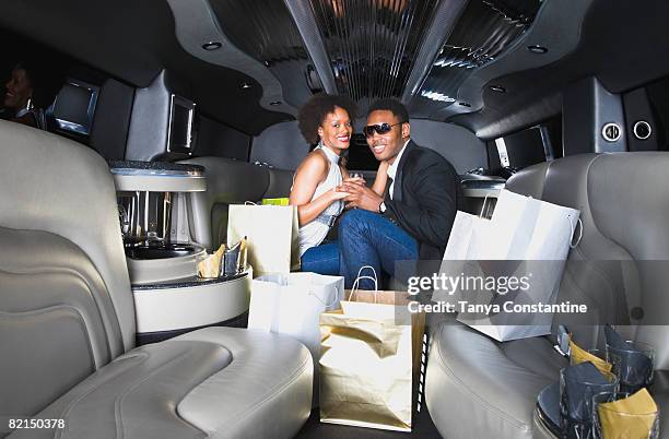 african couple with shopping bags in limousine - stereotypically upper class stock pictures, royalty-free photos & images