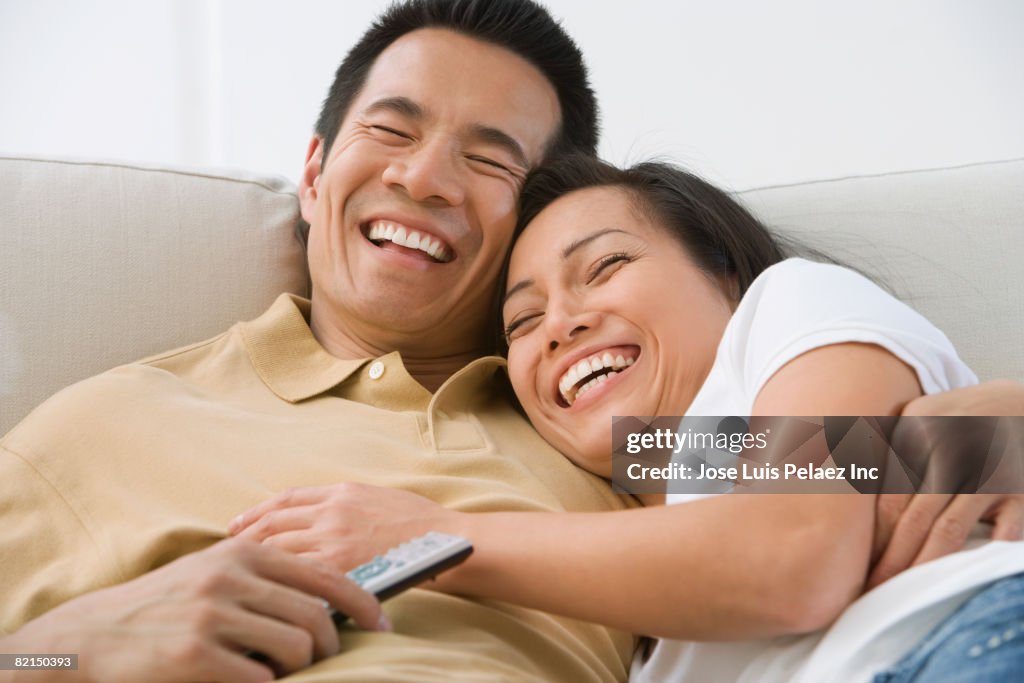 Asian couple laughing on sofa