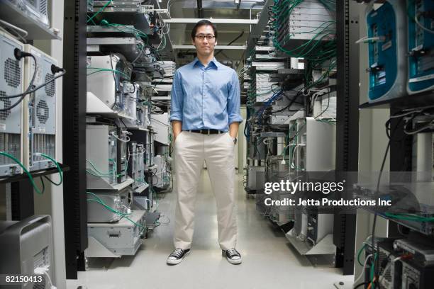 asian man standing in computer server room - good technology inc stock pictures, royalty-free photos & images