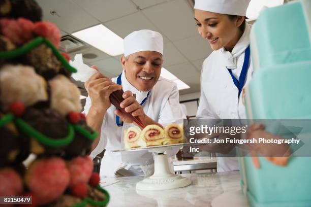 multi-ethnic pastry chefs decorating cake - decorating a cake fotografías e imágenes de stock