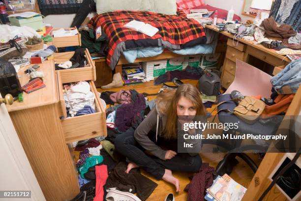 hispanic teenaged girl sitting in messy bedroom - messy fotografías e imágenes de stock