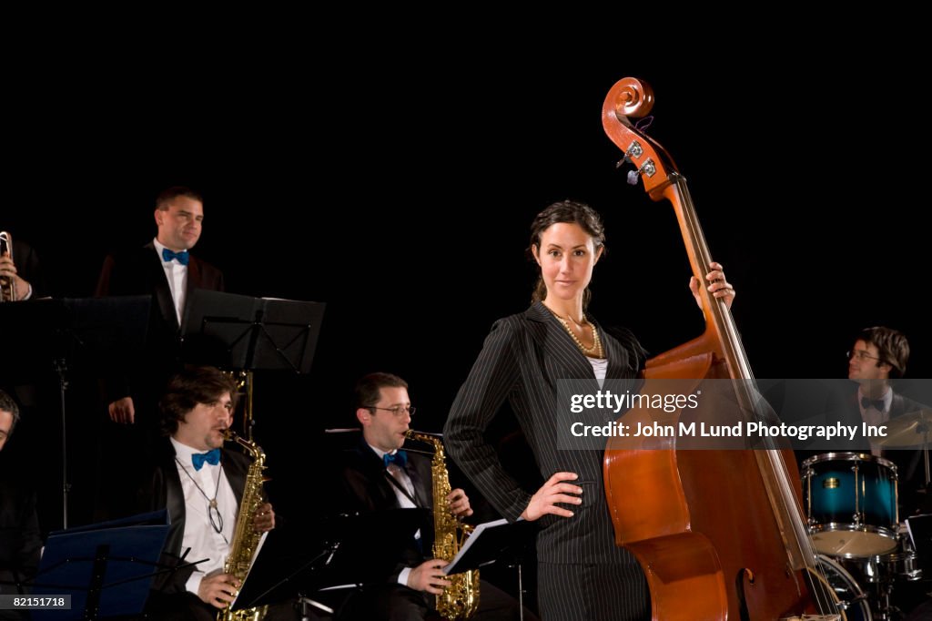 Woman holding upright bass in front of band