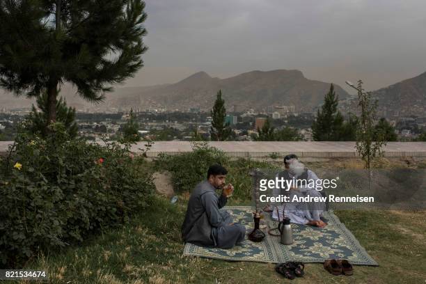 Men smoke a hookah in a park on Wazir Hill on July 19, 2017 in Kabul, Afghanistan. Despite a heavy security presence throughout the city, life...