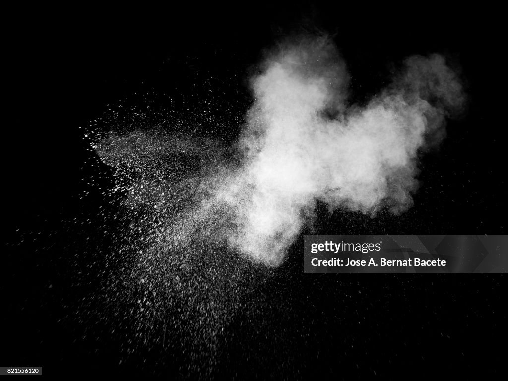 Forms and textures of an explosion of a powder of color white on a  black background