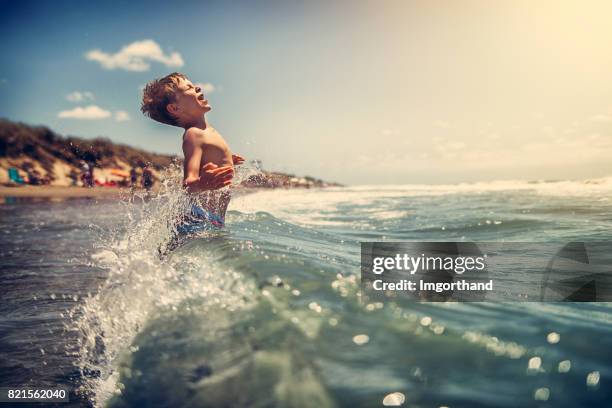 海の波で遊ぶ少年 - 水につかる ストックフォトと画像