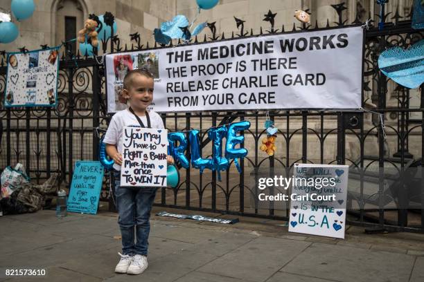 Young boy holds a placard given to him by his mother as supporters of of terminally ill baby Charlie Gard protest outside the High Court after the...