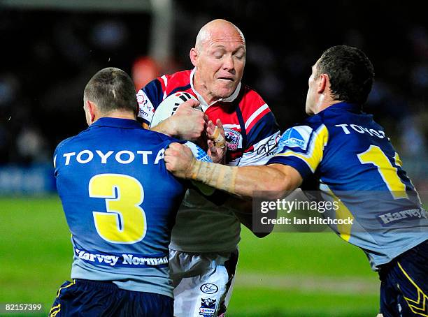 Craig Fitzgibbon of the Roosters is tackled by Mark Henry and Luke O'Donnell of the Cowboys during the round 21 NRL match between the North...