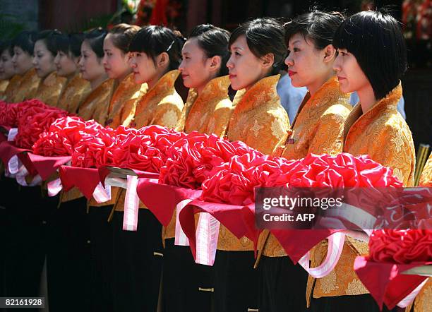 Chinese waitresses gather for a ceremony at a reopening of a popular Peking duck restaurant along the once historical street in one of Beijing's...