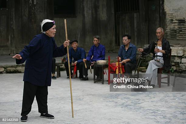 Folk artist 69-year-old Xu Shuqing, performs the 'Houhe Guxi', a traditional drama, at the Zhuoshui Township on August 2, 2008 in Qianjiang Tujia and...