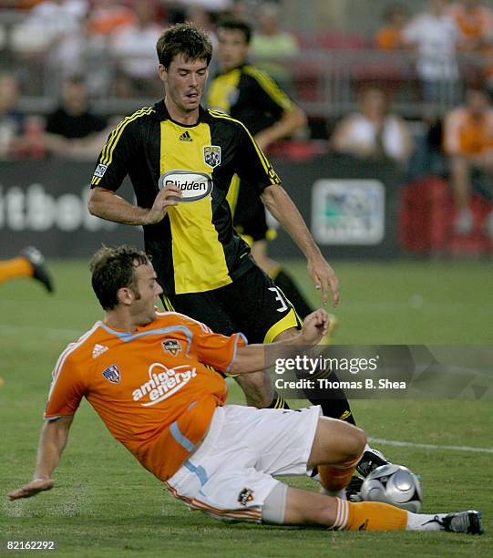 Brian Mullan of the Houston Dynamo slide tackles Brad Evans Columbus Crew on August 02, 2008 at Robertson Stadium in Houston, Texas.