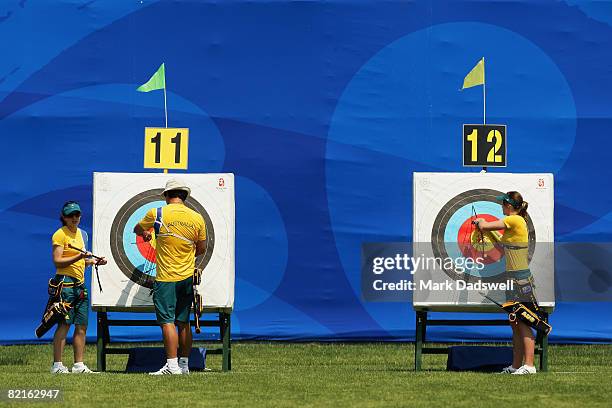 Lexie Feeney, Matthew Gray and Jane Waller of Australia withdraw their arrows from the targets during a practice session at the Olympic Green Archery...