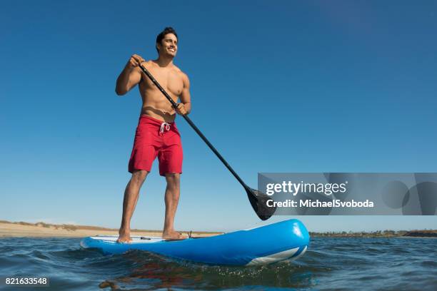 man stand up paddle boarding - board shorts stock pictures, royalty-free photos & images