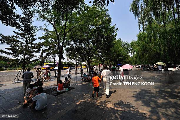 Oly-2008-China-environment-city-makeover by Gersende Rambourg Chinese protect themselves from the sun under the shades of trees at Tiananmen Square...