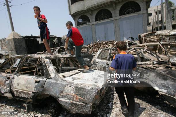 Palestinian children play on burnt out cars, one day after clashes between rival forces of Hamas and Fatah movements, on August 03, 2008 in the...