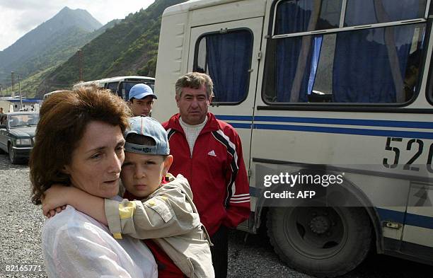 Refugees from a maverick Georgian region of South Ossetia leave a bus upon their arrival to Russian territory in a village of Tamisk, some 50...