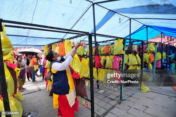 Woman arranging sandal or shoes of devotees come to offer ritual prayer during Shrawan Sombar festival at the premises of Pashupatinath Temple,...