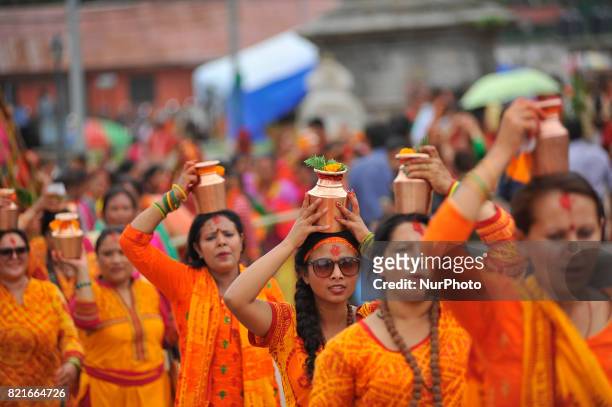 Nepalese devotees hold holy water to offer at the temple during Shrawan Sombar festival at the premises of Pashupatinath Temple, Kathmandu, Nepal on...