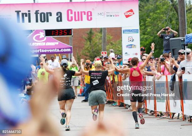 Relay team holds hands as they approach the finish line at the 10th annual Tri for a Cure triathlon at SMCC.