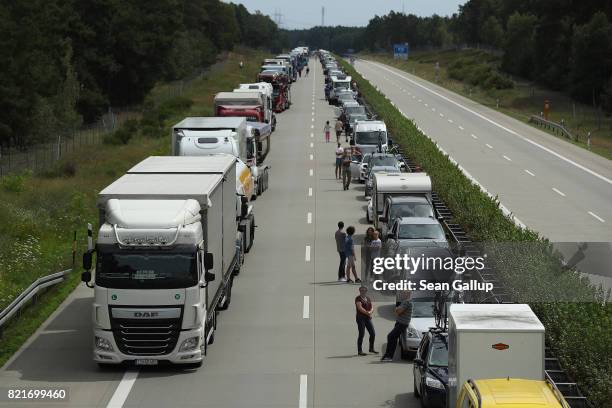 Travellers stand near their vehicles that they have parked in order to create a lane for emergency crews to get through following an accident in...