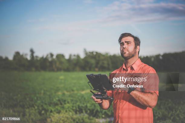 man farmer pilot using drone remote controller at sunset - radio controlled handset stock pictures, royalty-free photos & images
