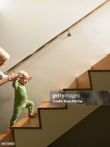 mother helping baby boy walk up stairs - family tree stockfoto's en -beelden