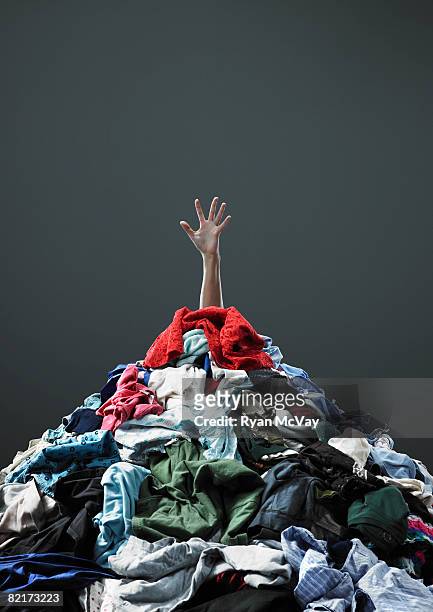 hand coming out of pile of clothing - clothes stock pictures, royalty-free photos & images