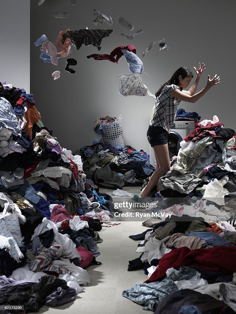 Woman throwing clothes in overflowing laundry room