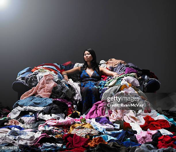 woman sitting on sofa surrounded by clothes. - accumulation stock pictures, royalty-free photos & images