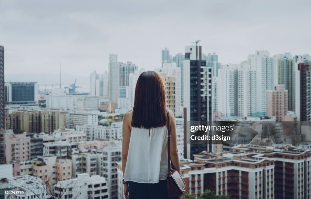 Rear view of woman overlooking busy and energetic cityscape of Hong Kong