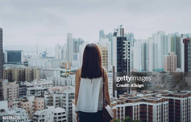 rear view of woman overlooking busy and energetic cityscape of hong kong - ergens overheen kijken stockfoto's en -beelden