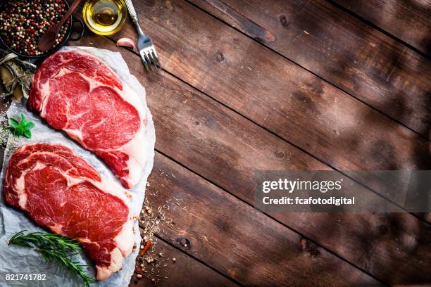 vers rundvlees biefstuk filets met koken abd kruiden ingrediënten op rustieke houten tafel - kalfsvlees stockfoto's en -beelden