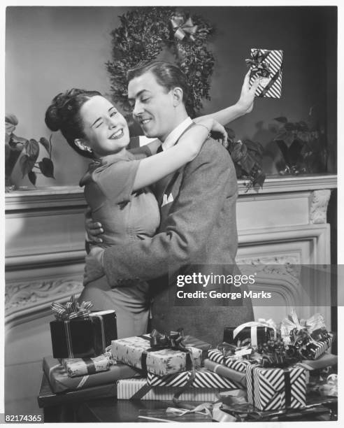 couple embracing at table with christmas presents, (b&w) - black and white christmas imagens e fotografias de stock