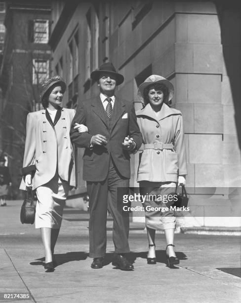 man and two women walking on sidewalk, (b&w) - george marks man fotografías e imágenes de stock