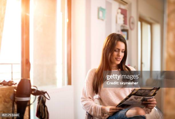 junge schöne frau lesen einer zeitschrift beim friseur. - catalogo stock-fotos und bilder