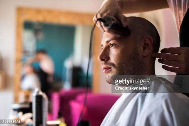 young man having his head shaved with electric razor at barber shop. - crew cut stock pictures, royalty-free photos & images