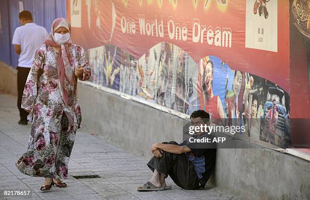 Ethnic Uighurs pass by a poster of the 2008 Beijing Olympics on a street in Xinjiang's famed Silk Road city of Kashgar in China's far northwestern,...