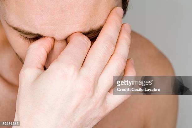 man holding bridge of nose - pain face stock-fotos und bilder