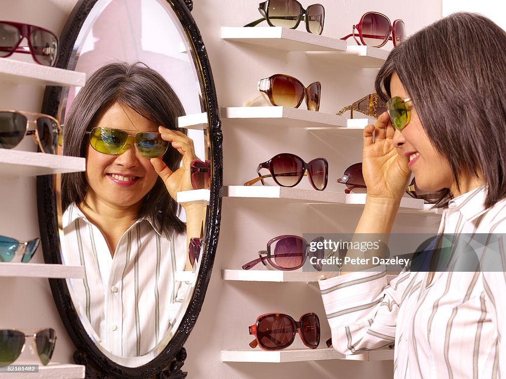 Women choosing sunglasses in mirror