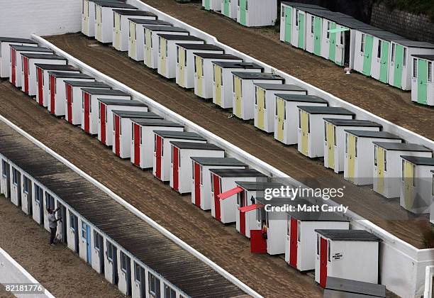 Man works on beach huts on an empty beach on August 5, 2008 in Newquay, Cornwall, England. The value of beach huts is seen as a financial climate...